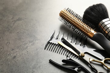 Different hairdresser's tools on grey table, closeup. Space for text