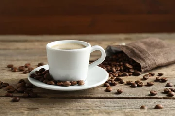 Zelfklevend Fotobehang Aromatic coffee in cup and beans on wooden table, closeup © New Africa