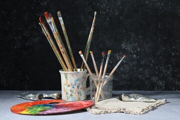 Brushes, palette and color paints on grey table