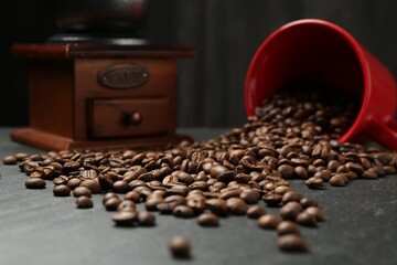 Aromatic coffee beans and grinder on black table, closeup