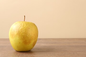 One rotten green apple on wooden table. Space for text