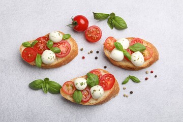 Tasty sandwiches with mozzarella cheese balls, tomato and basil on light grey table, flat lay