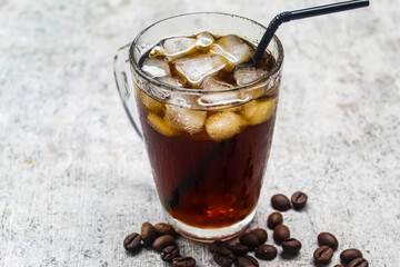 a glass of iced coffee with a straw and coffee beans