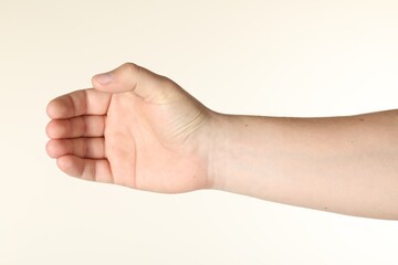 Man holding something in hand on beige background, closeup