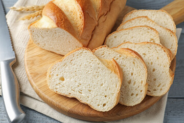 Sliced bread and knife on grey wooden table, closeup