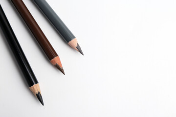 Three different eyebrow pencils on white background, top view. Space for text