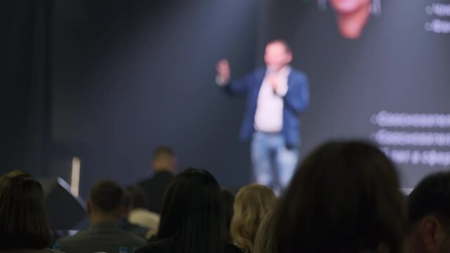 Audience attentively listening to a presenter on stage during a professional business conference.