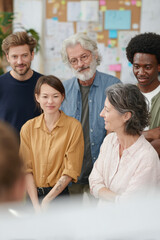Midday in a spacious office with soft lighting A diverse group of employees from different generations is working together