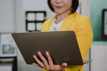 An Asian female employee in a yellow shirt is summarizing the results of the first quarter of this year.
