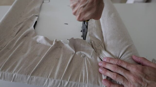 Man hands using a long nose pliers to take out staples