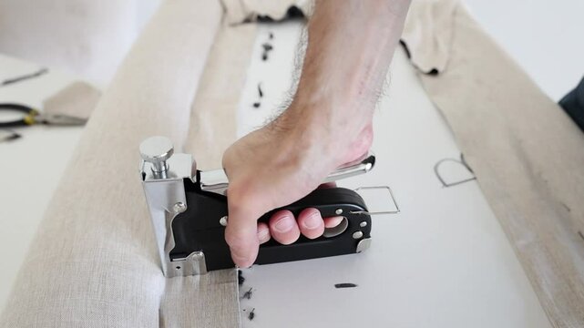 Man using professional utility stapler tool for fix fabric