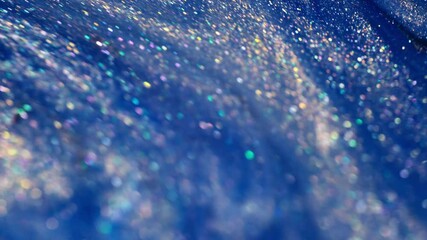 A close-up view of shimmering blue glitter with rainbow reflections, suggesting ink mixing - Powered by Adobe