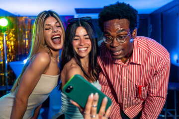 Friends taking selfie at party with smartphone