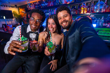 Friends taking selfie while drinking cocktails at the bar