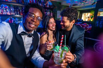 Friends toasting cocktails at pub, celebrating with mojitos and festive atmosphere