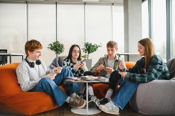 Group of teenagers playing board game in modern office space
