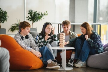 Students playing engaging board game jenga in modern university lounge
