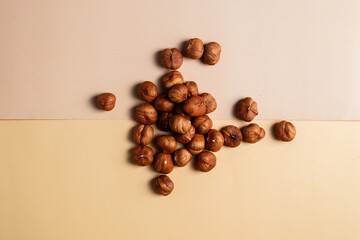 A collection of shelled hazelnuts on a two-tone background.