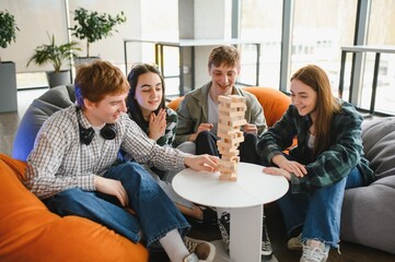 Friends playing stacking tower wood block game on bean bag chairs