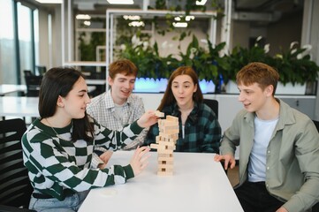 Young office colleagues playing wooden block game at work