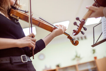 teenage violinist girl learning a piece from notes in a music class with a teacher. Musical development