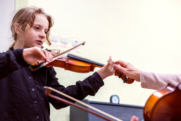 correction of finger placement on the fingerboard while playing the violin by a teacher. Musical...