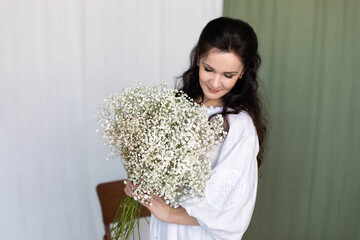 caucasian attractive woman stands in national ethnic ukrainian folk traditional dress holds bouquet...