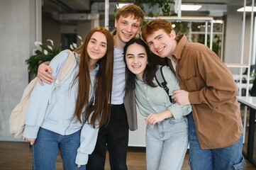 Happy students embracing and smiling together in university hall