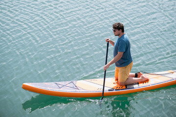 Young man rowing sup board after water surf session