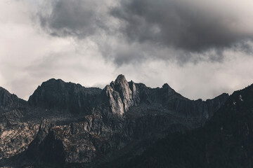 clouds over the mountains on  a moody afternoon in the alps; dark clouds in the sky and illuninated...