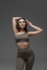 Model poses in stylish brown workout outfit with a confident expression in a studio setting
