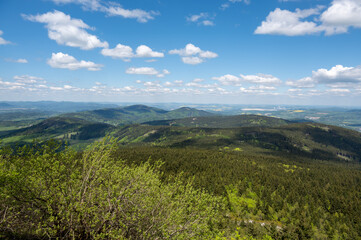 Fototapeta premium View from Jested mountain with the stone formation Virive kameny in the foreground and the city of Liberec stretching in the background under a clear blue sky.
