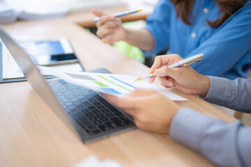 Business colleagues reviewing financial data and using laptop computer, working together in office,...