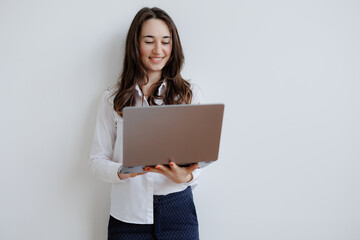 Fototapeta premium Young woman smiling while holding a laptop and working at home during daytime in a modern indoor setting