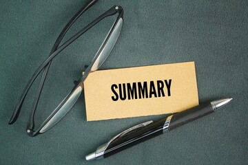 Glasses pen and paper with the word summary