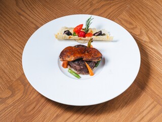 Beef tenderloin with foie gras and fruit garnish on white plate
