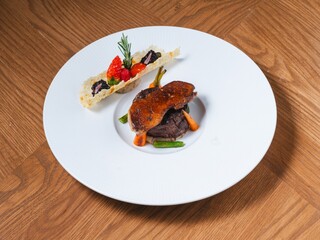 Beef tenderloin with foie gras and fruit garnish on white plate