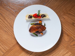 Beef tenderloin with foie gras and fruit garnish on white plate
