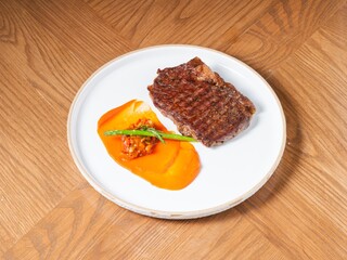 Grilled beef steak with sweet pepper sauce and asparagus on white ceramic plate