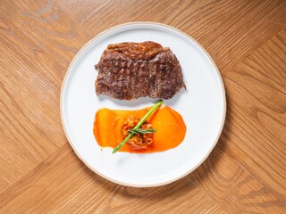 Grilled beef steak with sweet pepper sauce and asparagus on white ceramic plate