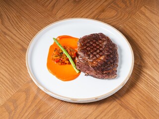 Grilled beef steak with sweet pepper sauce and asparagus on white ceramic plate