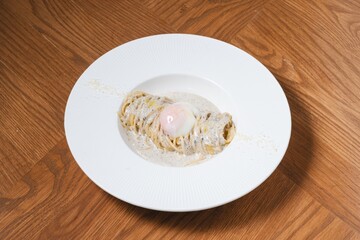 Truffle cream pasta with onsen egg and parmesan cheese on white plate