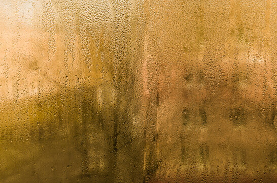 wet glass background. Cozy but damp: steamy window with water drops in warm room.