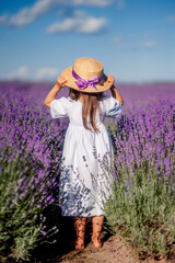 girl in a white dress and hat stands in a field of lavender