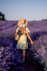 girl child in a yellow dress and a straw hat in a field of lavender