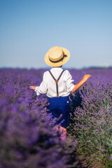 boy in a hat and shorts with suspenders walks in a field of lavender