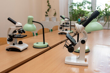 Microscopes and desk lamps in a biology classroom prepared for laboratory work or science education