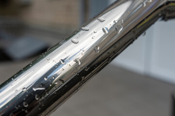 Close-up of wet stainless steel handrail with water droplets on a rainy day, showing texture and...