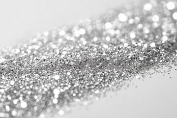 Silver glitter sparkles against a bright white background surface. Use it to add shine to your designs and holiday themed projects.