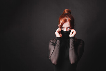 mysterious lady or woman with red hair and elegant black dress concealing part of her face with...